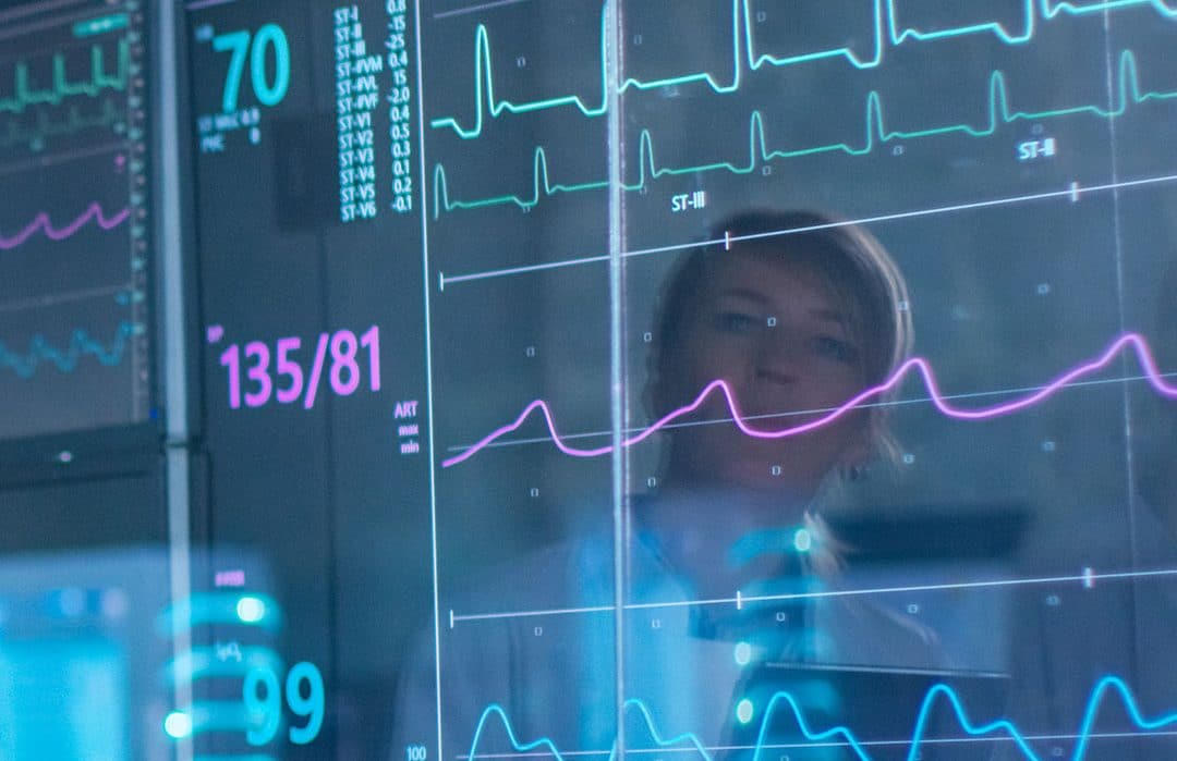 Sport Scientist Holds Tablet and Supervises EKG Status. Laboratory with High-Tech Equipment.